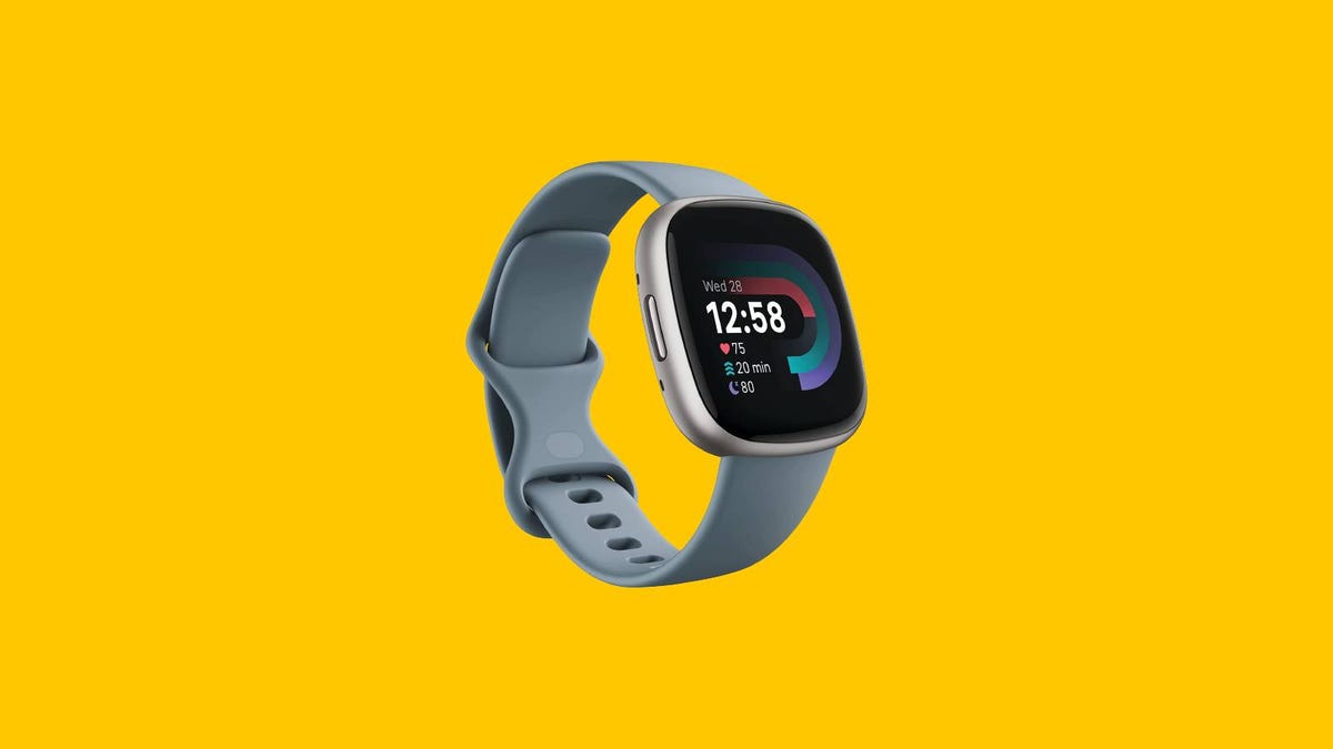 A  Fitbit Versa 4 fitness smartwatch is displayed against a yellow background.