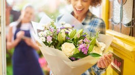 A woman holds a bouquet and smiles.
