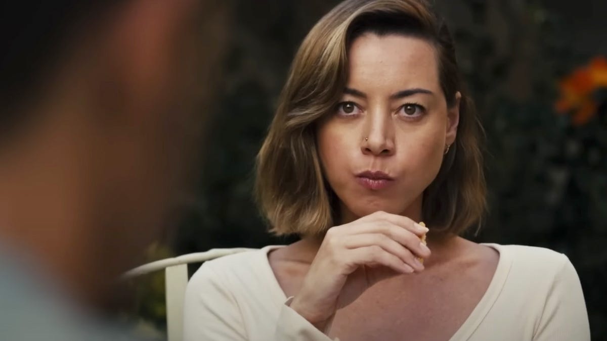 Midshot of Aubrey Plaza as Emily, eating at a table outside