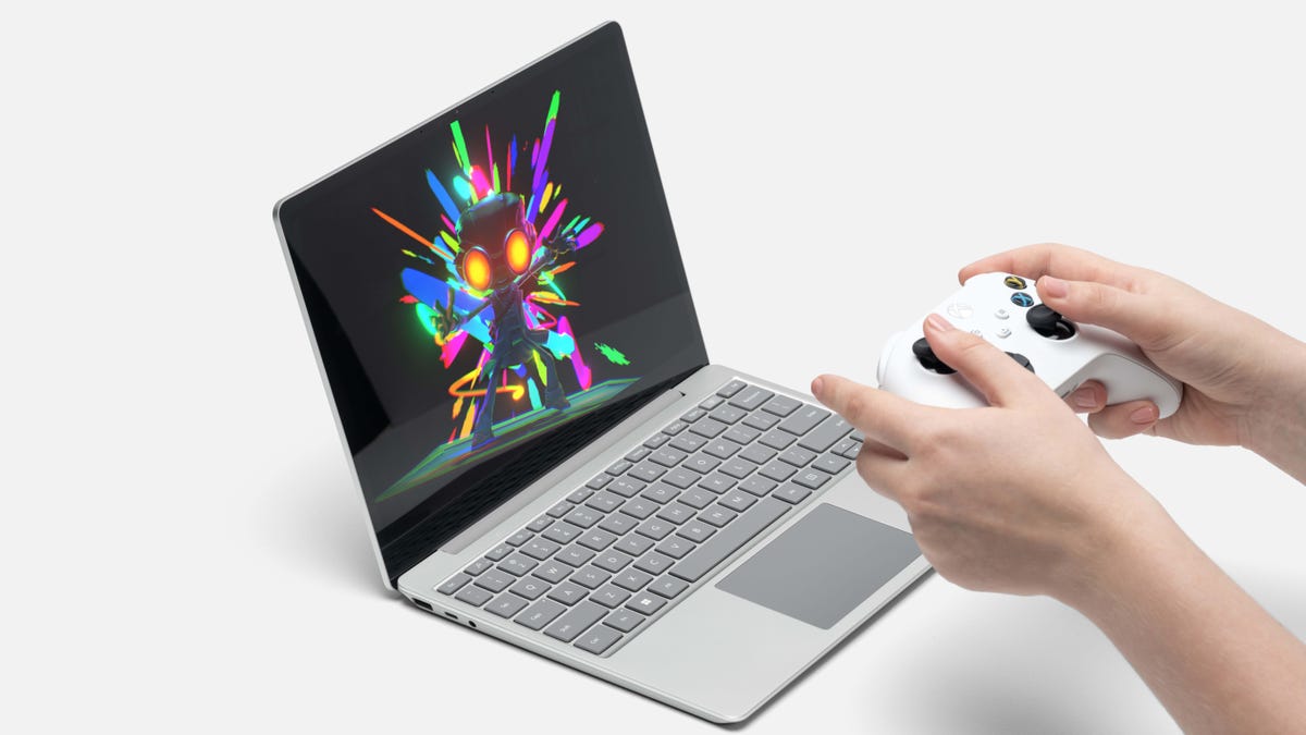 Hands holding a controller above an open Microsoft Surface Laptop Go 2 