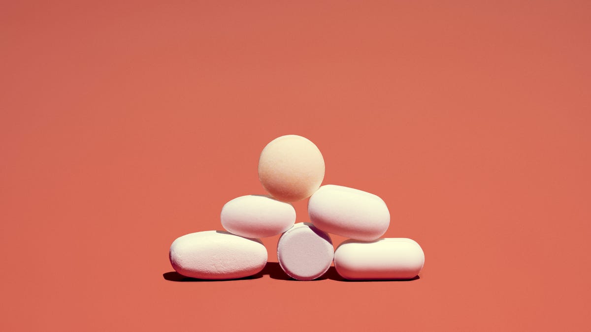 A pyramid of pills against a coral background 