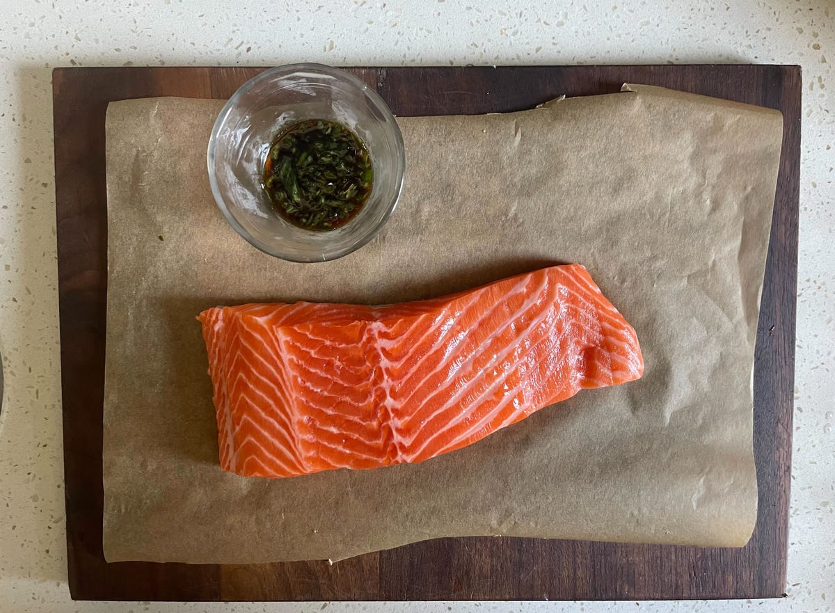 raw salmon filet on cutting board with ramekin of sauce
