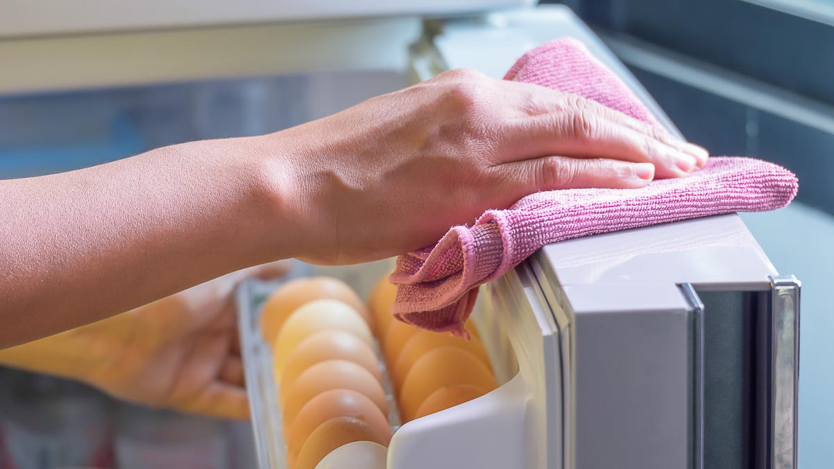 Hand with rag cleans fridge door