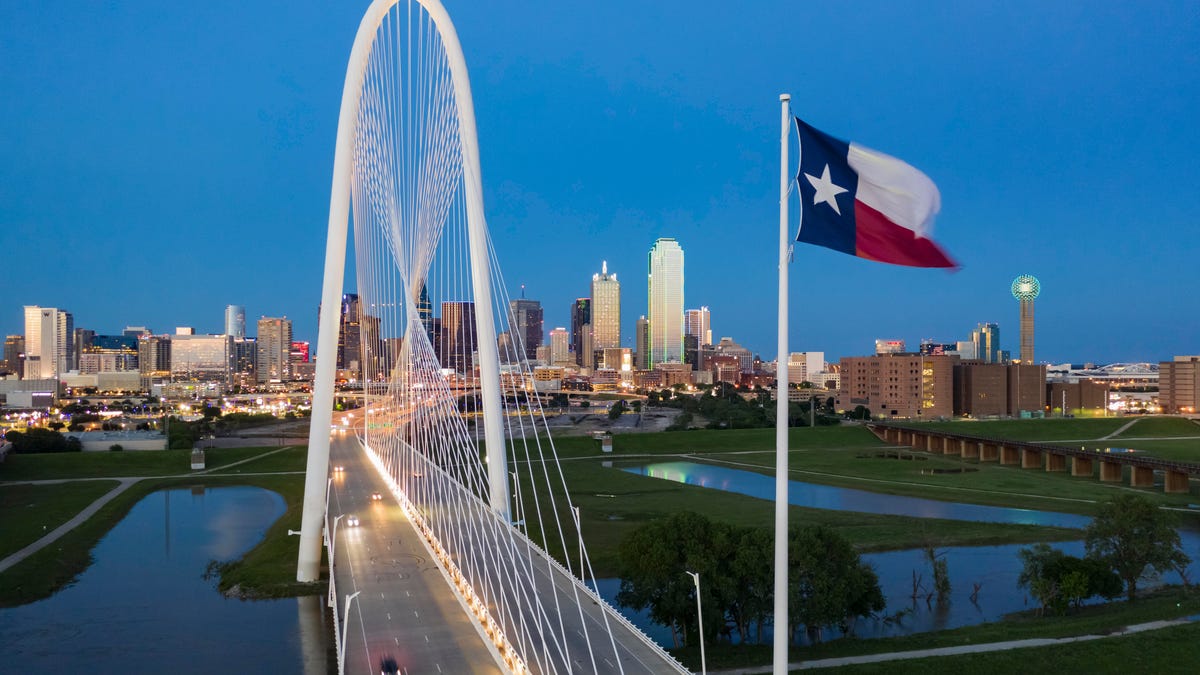 Elevated View of the Margaret Hunt Bridge and the Dallas Skyline at Dusk with the Texas state flag waiving