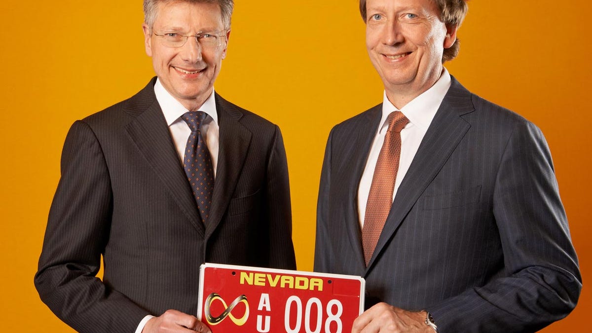 Continental CEO Elmar Degenhart and CFO Wolfgang Schaefer hold a red license plate that gives them permission to test autonomous vehicles in Nevada.