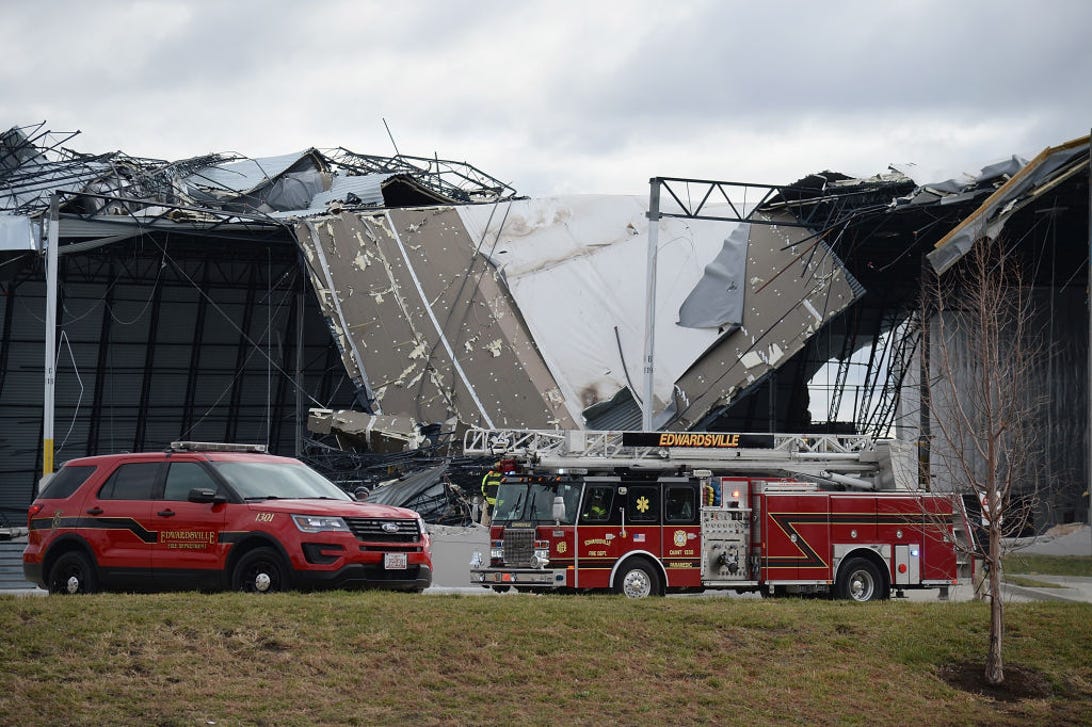İlk müdahale ekipleri 11 Aralık 2021'de Illinois, Edwardsville'de hasar görmüş bir Amazon Dağıtım Merkezi'ni çevreliyor.