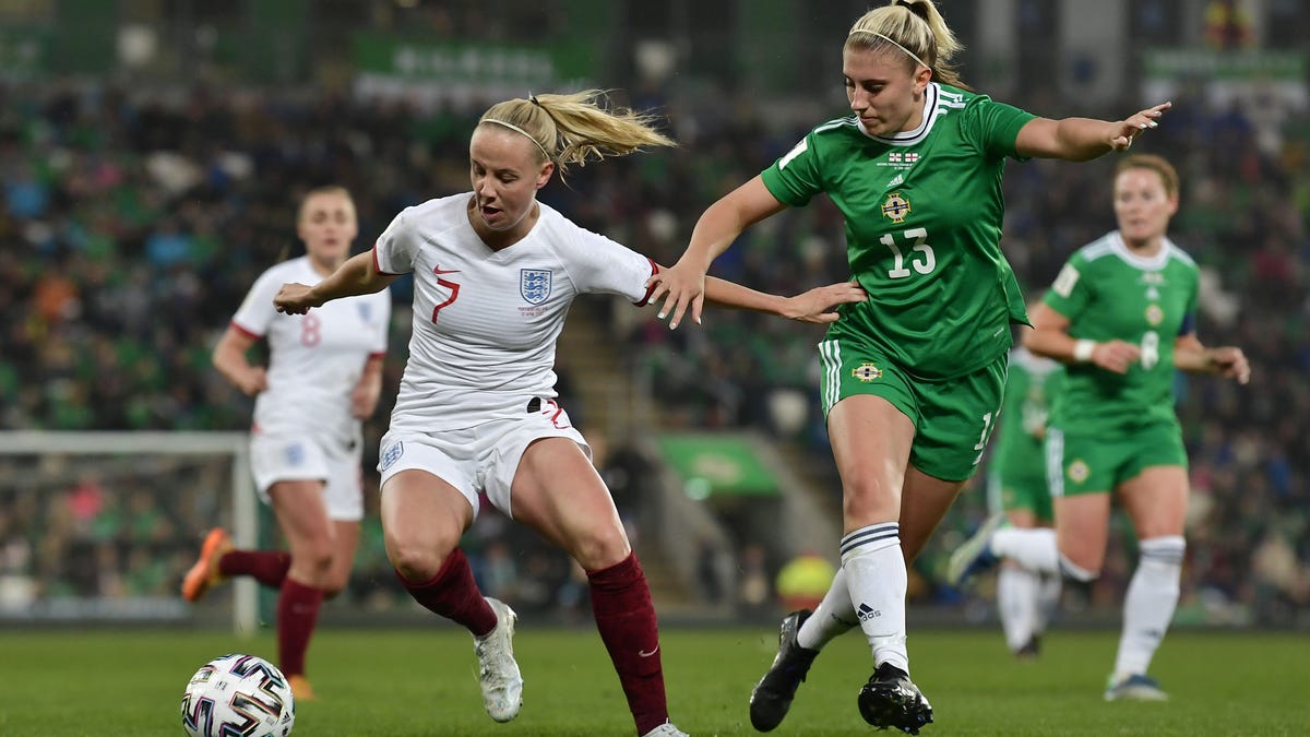 Beth Mead in England's all-white kit keeps the ball away from Kelsie Burrows in the green kit of Northern Ireland during a FIFA Women's World Cup 2023 Qualifier group.