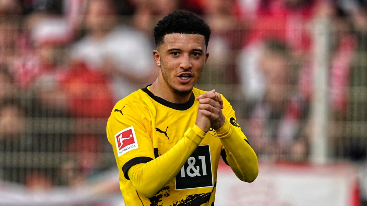 Jadon Sancho of Borussia Dortmund clasping his hands together, smiling.