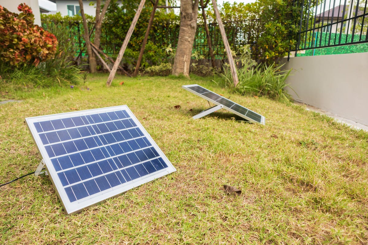 Dos pequeños paneles solares en el suelo de un jardín.