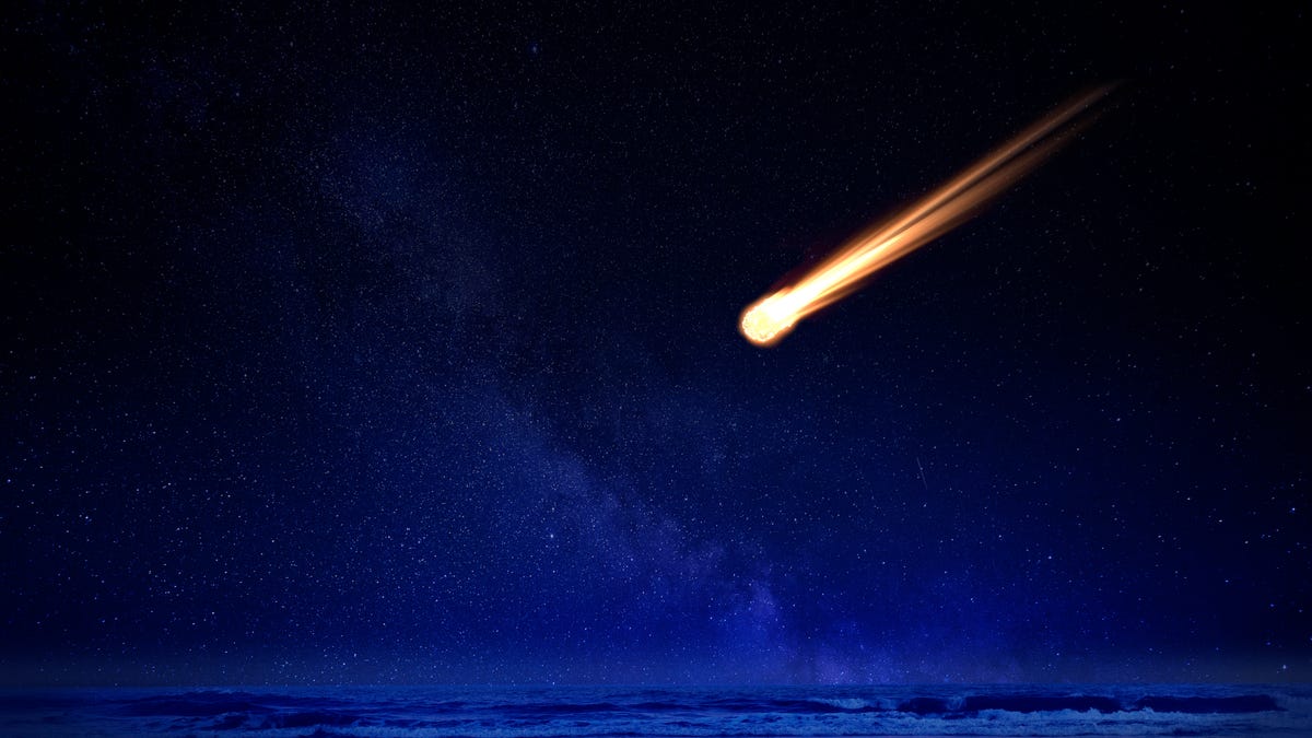 Meteor in night sky falling over ocean