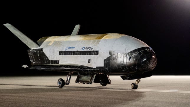 X-37B space plane on the runway resembles a small space shuttle with white top and black belly.
