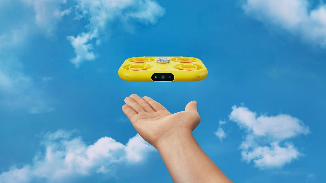 Pixy drone flying away from a hand against a bright blue sky with fluffy clouds
