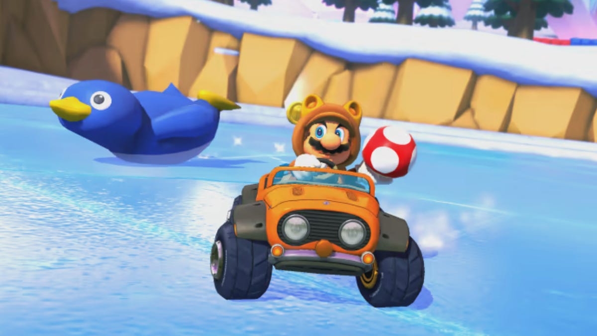 Tanooki Mario prepares to use a mushroom as penguin slides behind him on Mario Kart 8&apos;s Snow Land track