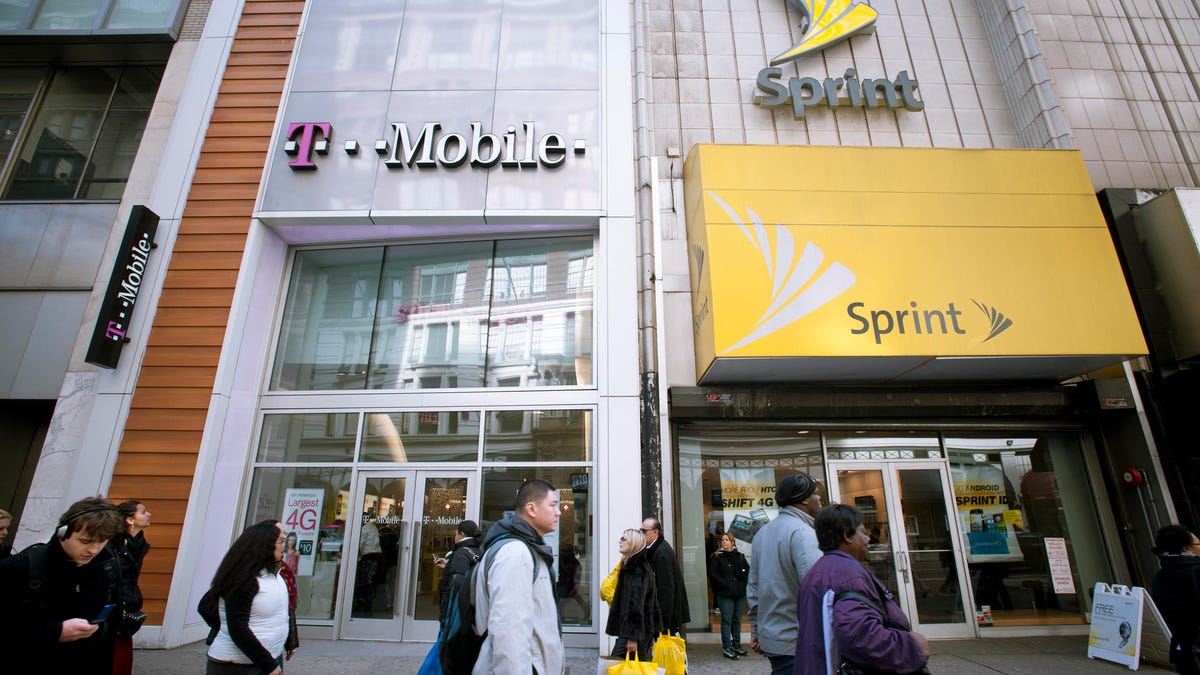 Sprint and T-Mobile storefronts, side by side on a street.