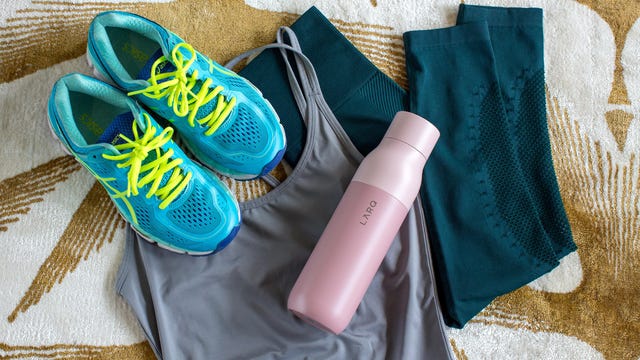 fitness clothes, blue-yellow sneakers and a pink water bottle laid out on floor