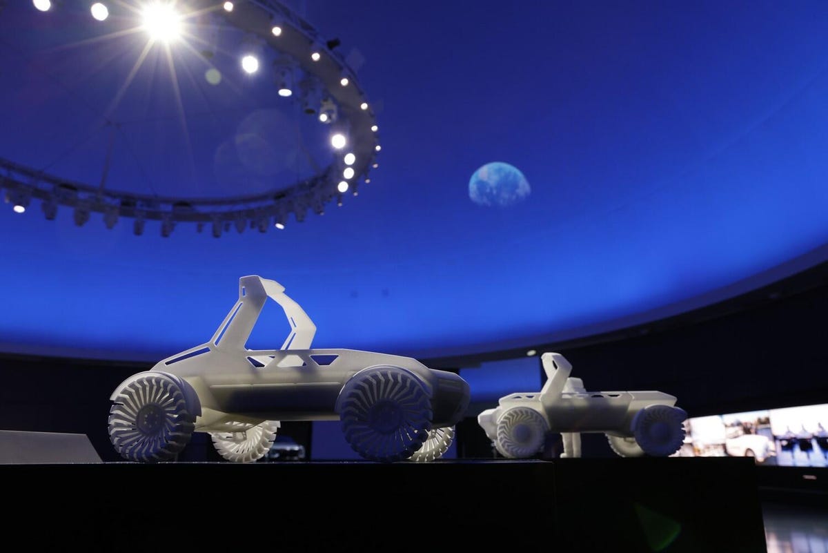 Two milky-white, 3D-printed rovers, each with big wheels and exposed roll hoops.