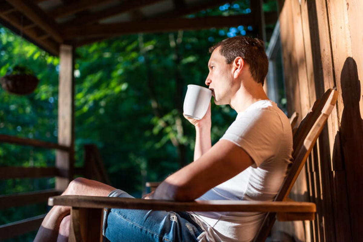 Man sitting in the sun on his porch while drinking coffee