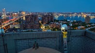 NYC Mesh volunteer adjusting antenna on the top of a roof with night views of the city