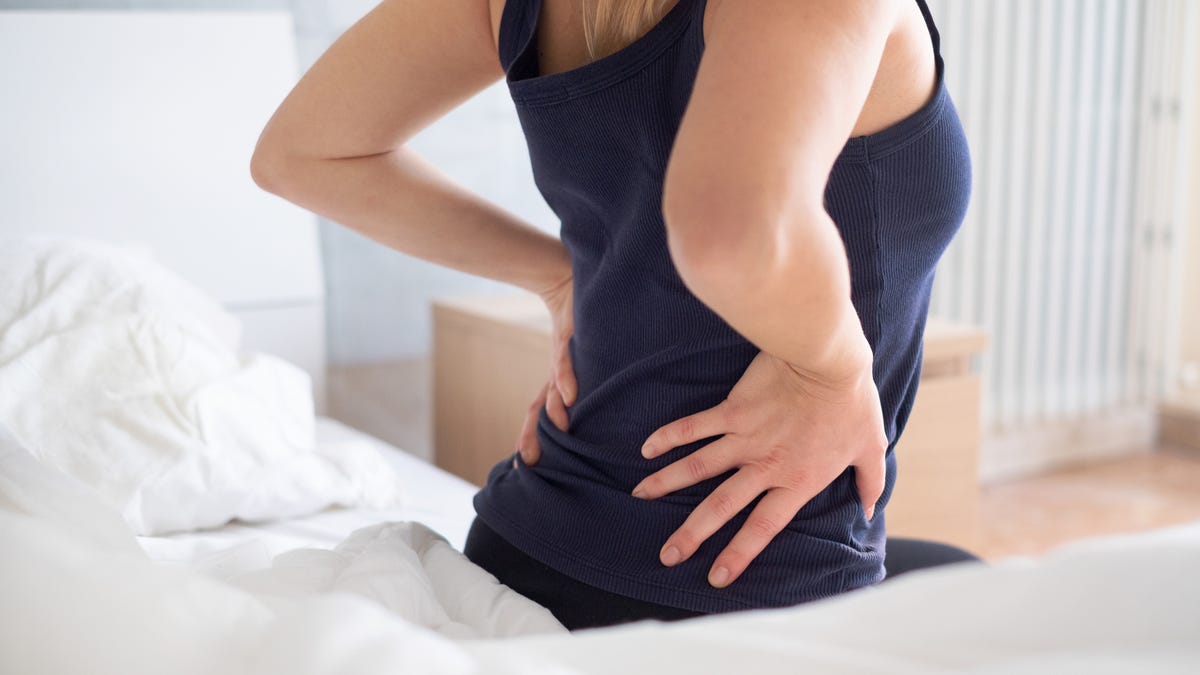 Woman on the edge of bed feeling back pain