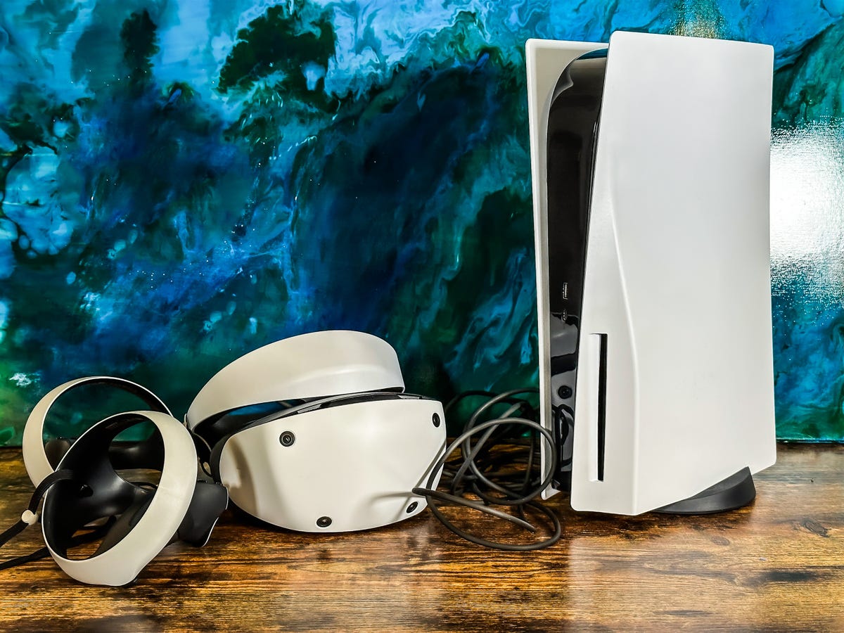A PSVR 2 headset next to the PlayStation 5 on a wooden table