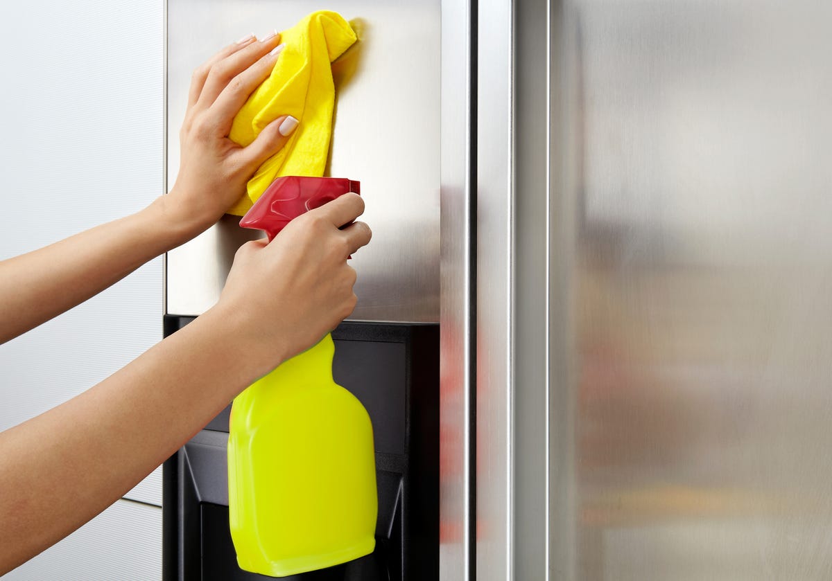 Woman Cleaning Stainless Steel Refrigerator Surface