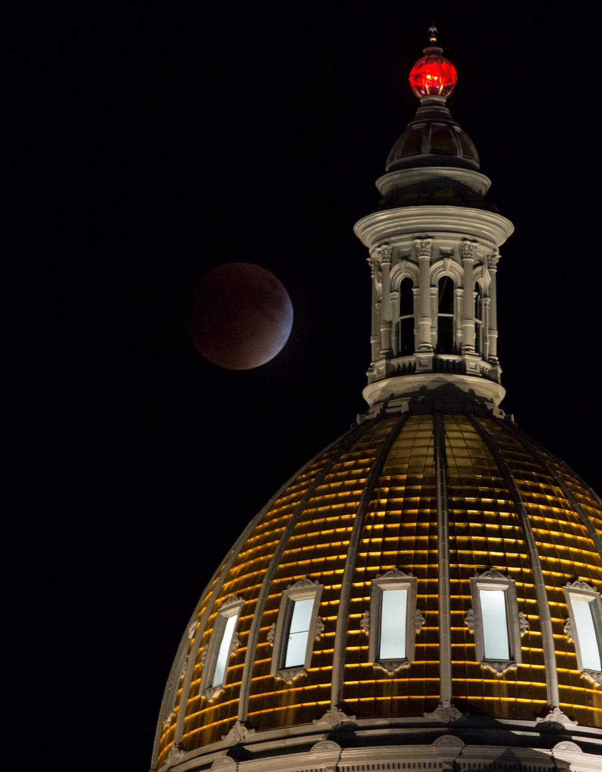 A perigee full moon during a total lunar eclipse behind the Colorado State Capitol.