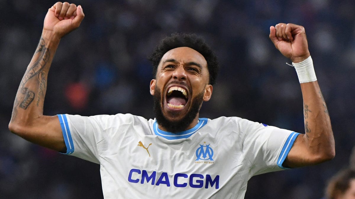 Pierre-Emerick Aubameyang of Marseille celebrating, wsmiling, shouting, both arms raised above his head, fists clenched.