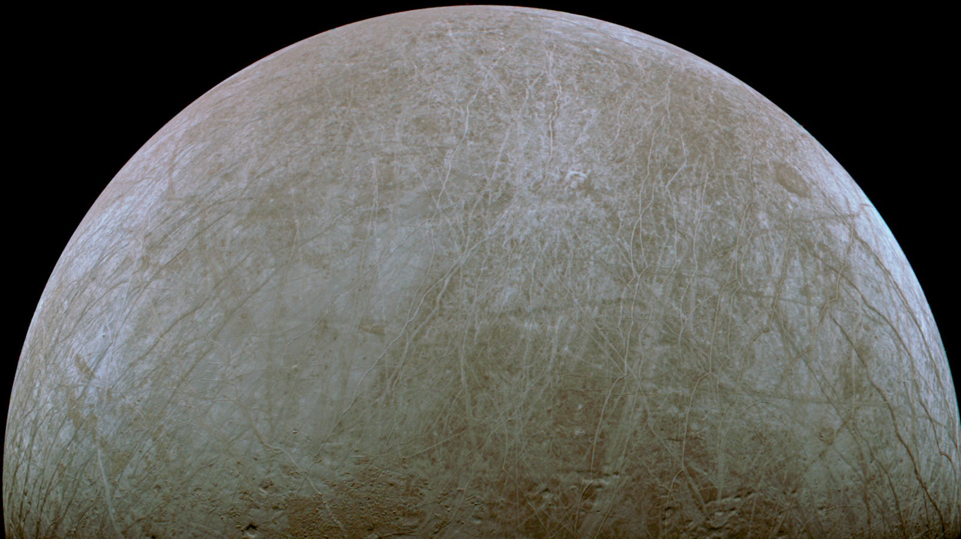 Jupiter's moon Europa shows off its icy striations and craters in a half-moon view against black.