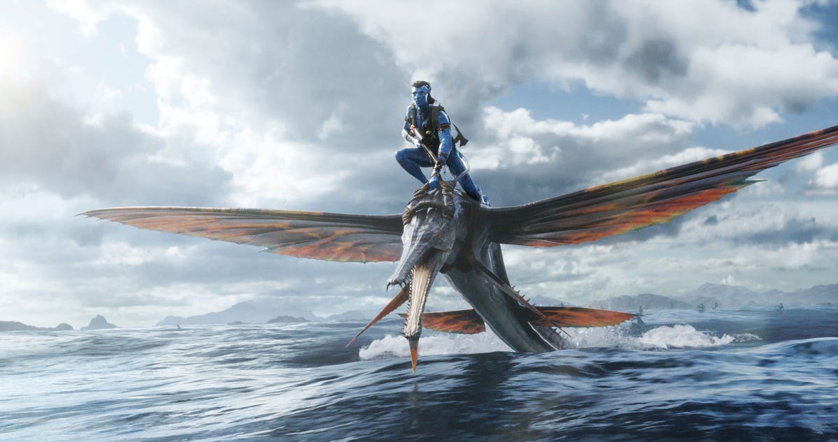A blue alien rides a flying fish across the sea in Avatar 2 The Weight of Water.