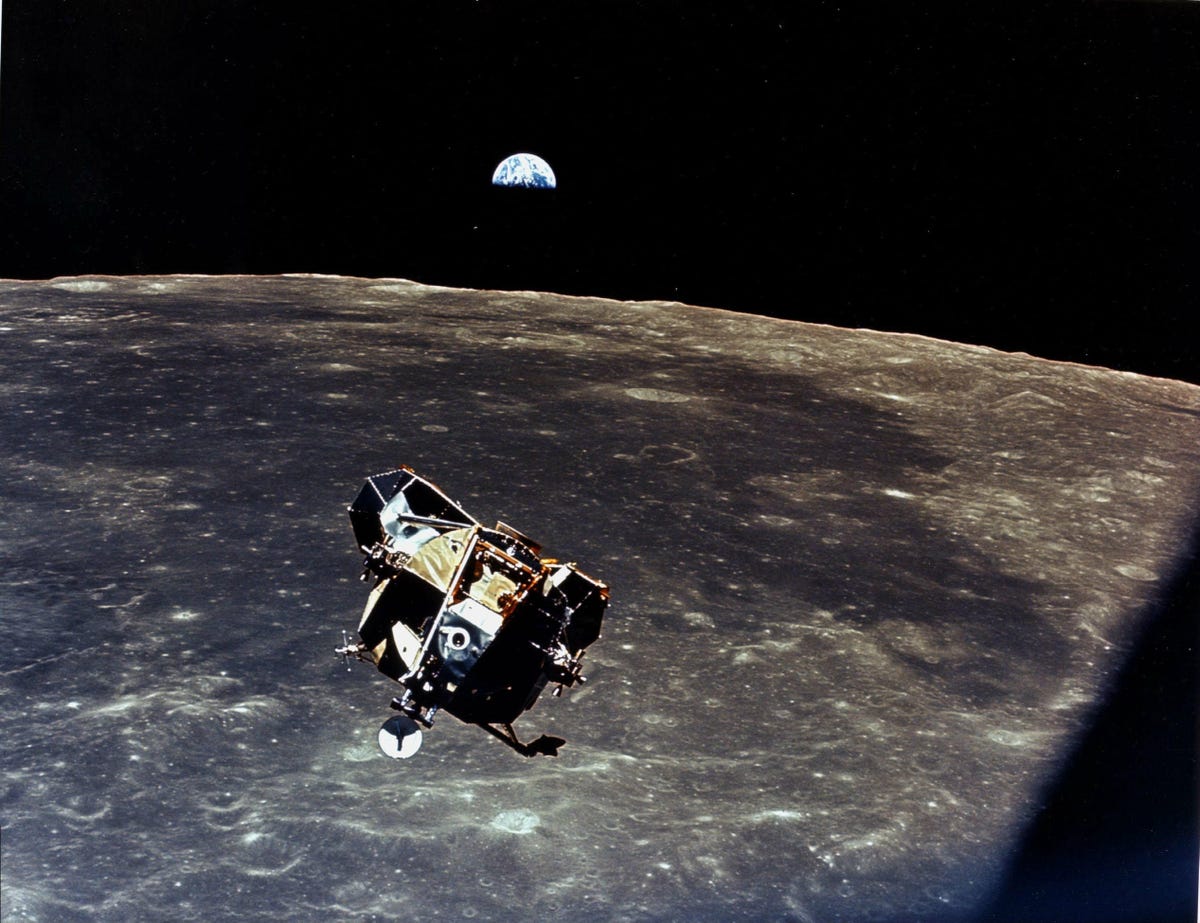 Apollo 11 lunar module in flight above the moon, with Earth in the background.