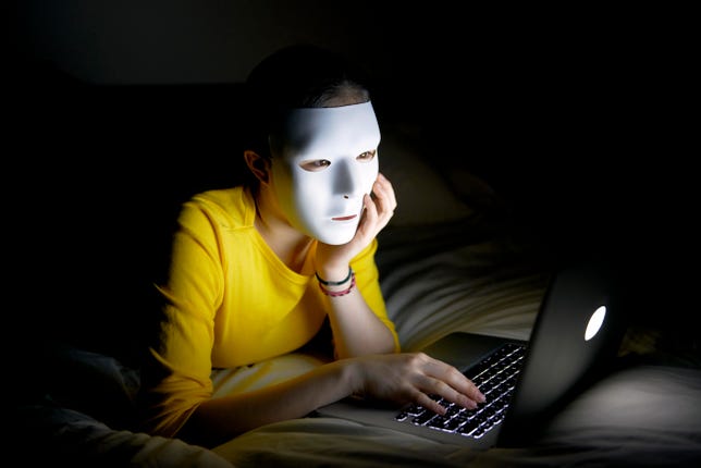 Anonymous teenager in mask on internet at night