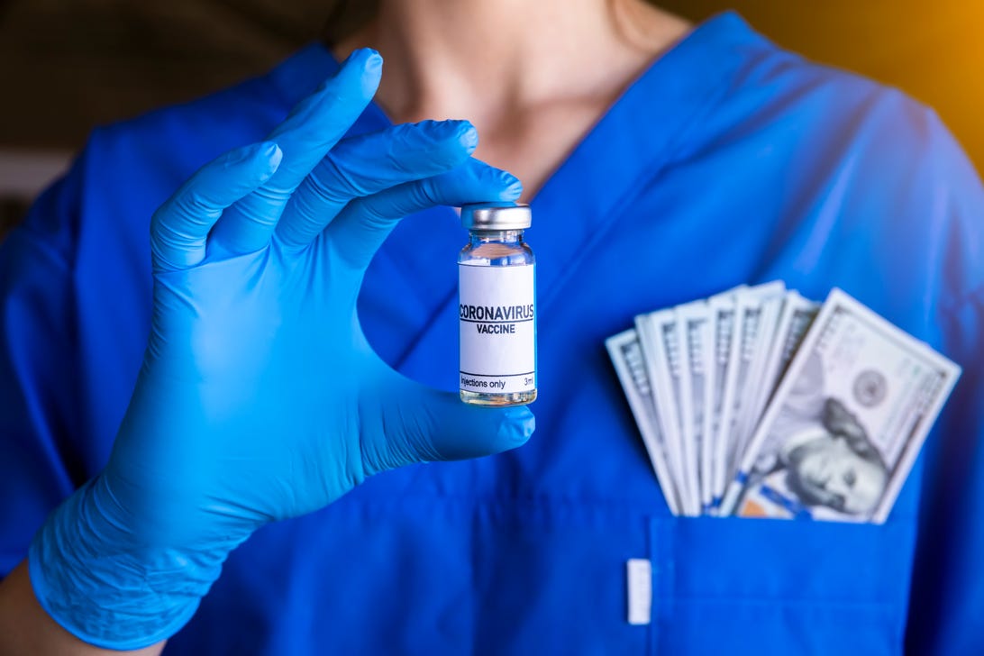 Health care worker holds vaccine vial with cash in their pocket.