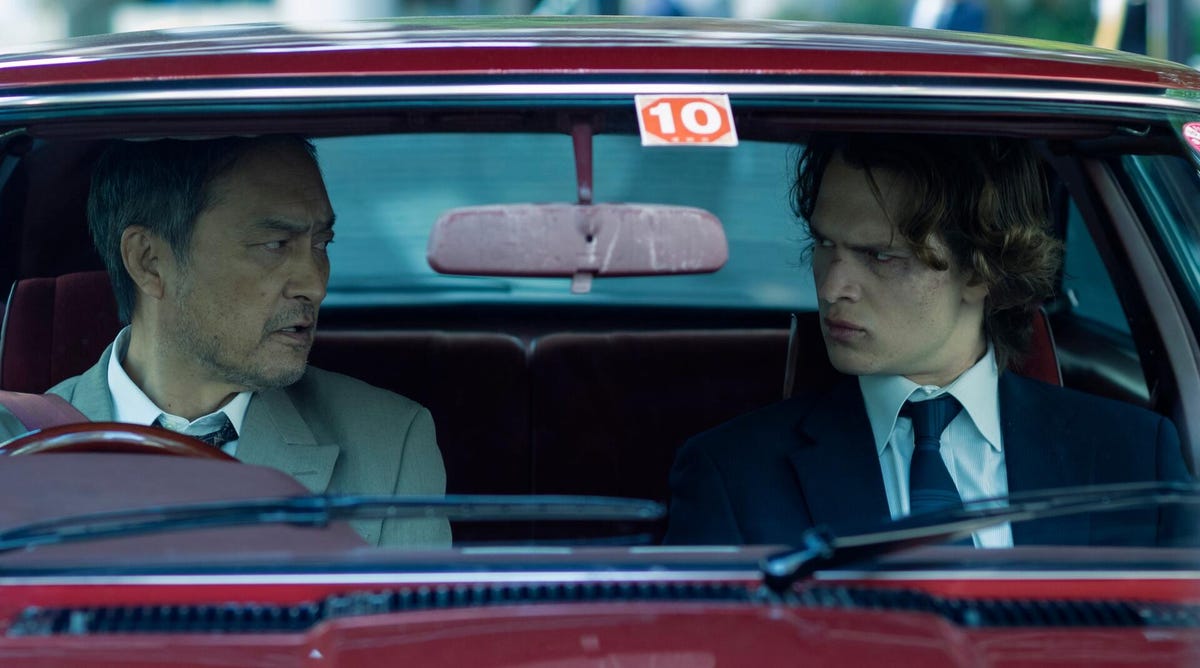 ken watanabe and ansel elgort sit in a red car in tokyo vice