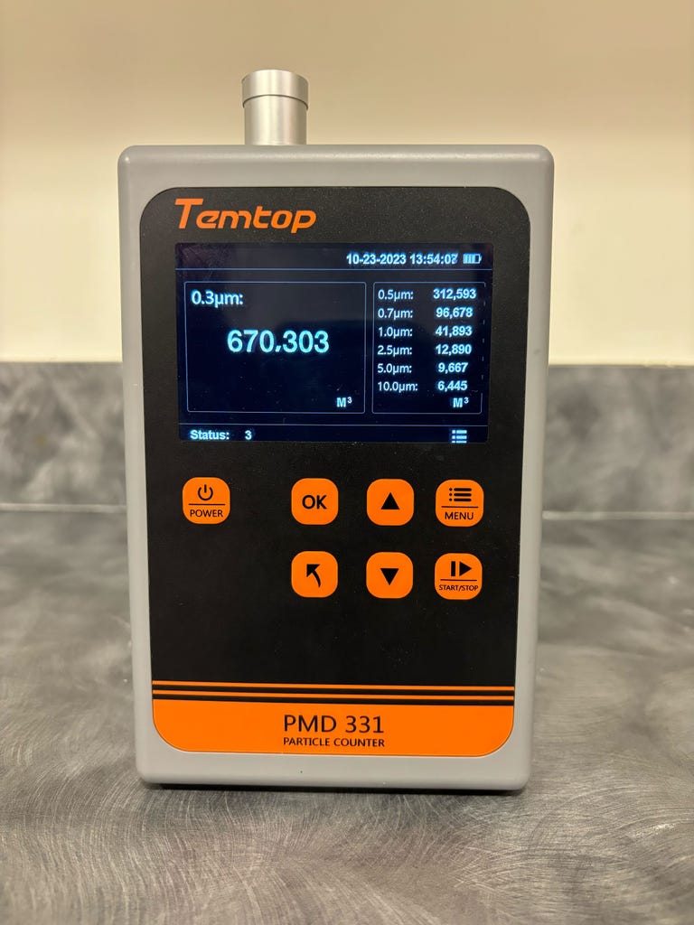 A Temtop particle counter sits on a shelf. We use this to track the number of small and fine particles in the air of our test chamber during air purifier tests.