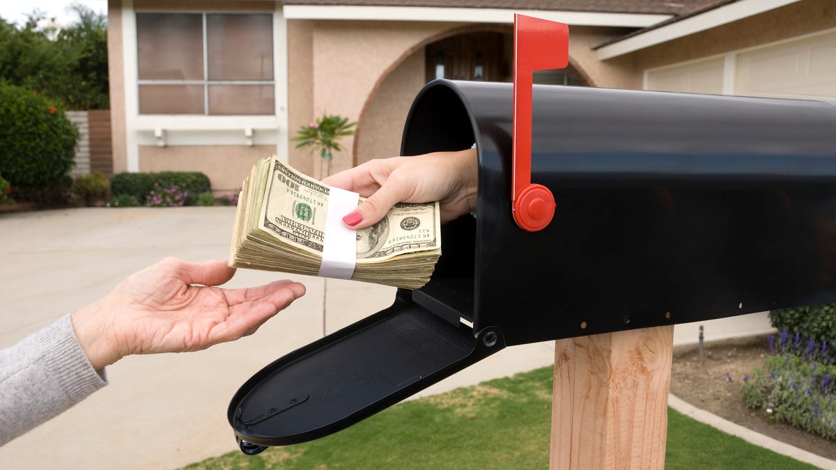 Hand reaches out of mailbox holding wad of cash