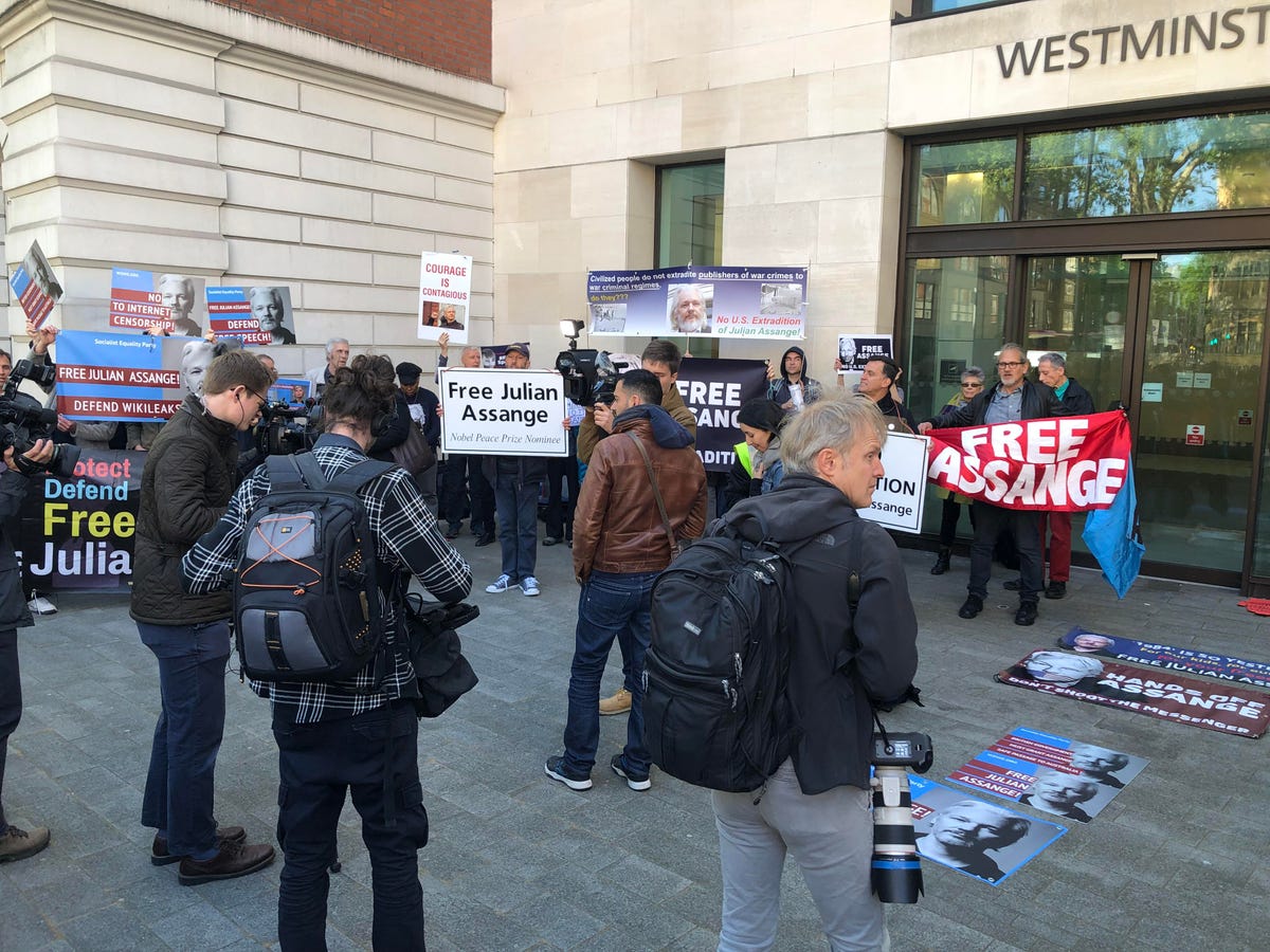 Protesters outside Westminster Magistrates Court in London, holding signs saying "Free Julian Assange."