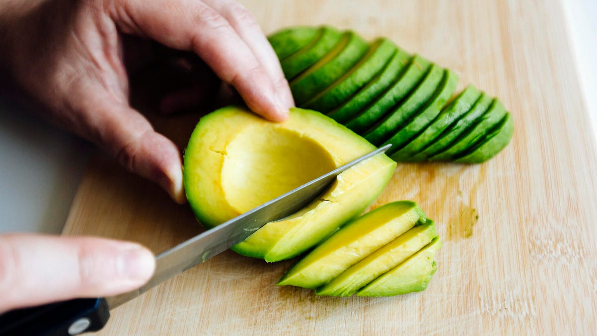 A person slicing an avocado with a knife