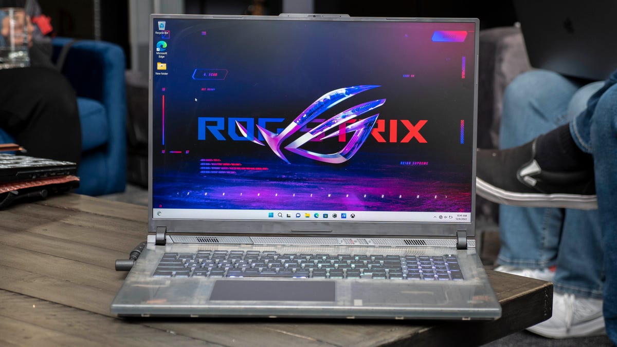 The ROG Strix SCAR 18 gaming laptop is sitting on a wooden table.