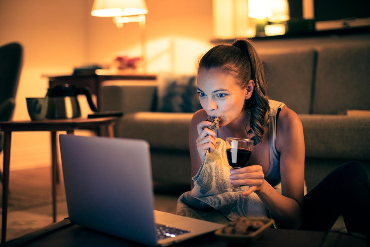 A woman watches a movie on laptop while eating