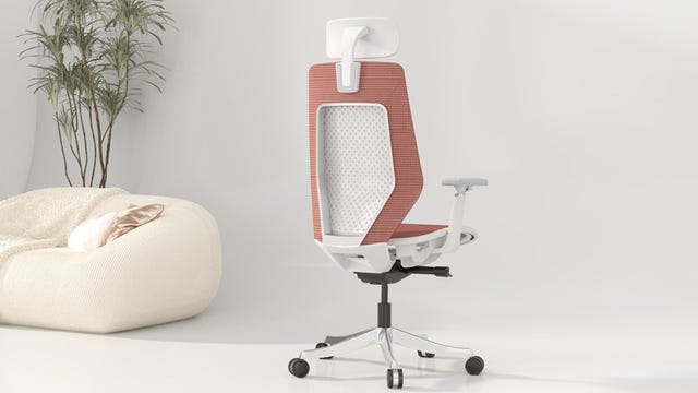 A coral backed luxury office chair with been bag in the corner.