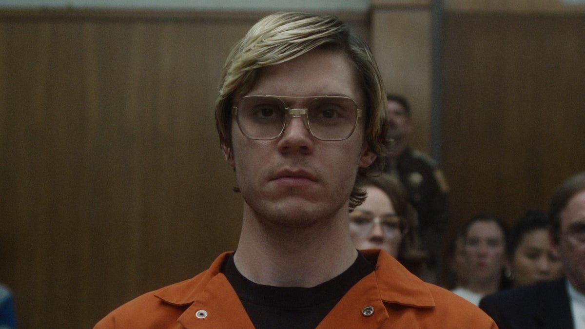 Evan Peters as Jeffrey Dahmer, wearing an orange jumpsuit in a court room