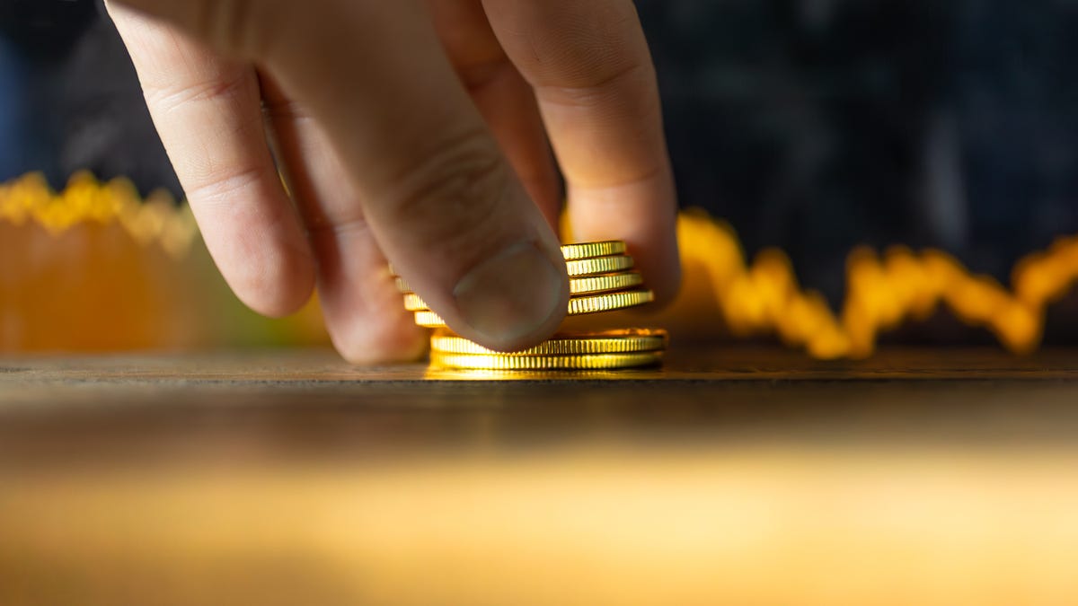 A hand placing gold coins on a table