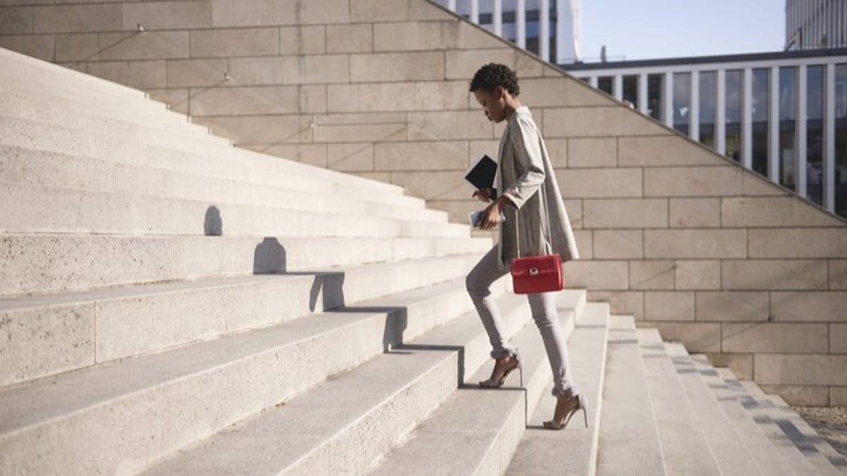 woman walking up stairs wearing heels and a purse