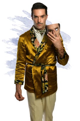 Man in a gold smoking jacket holding a mask of his own face
