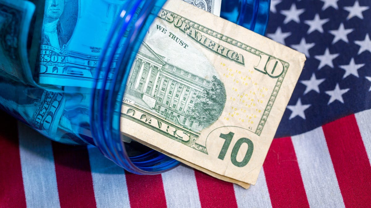$10 dollar bills inside a blue glass jar with an American flag background