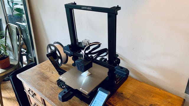 An Anycubic Vyper 3D printer sits on top of a wooden desk.