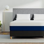 Amerisleep AS2 memory foam mattress in a bedroom with a gray headboard.