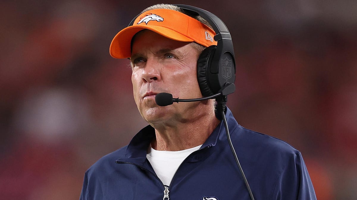 Denver Broncos head coach Sean Payton wearing a cap and headset looking to his right.