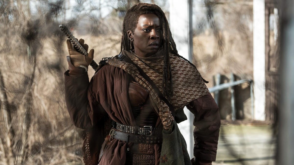 danai gurira as michonne stands in forest and holds sword handle