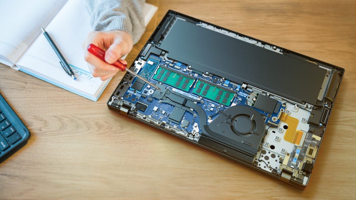 Someone fixing a laptop with a screwdriver